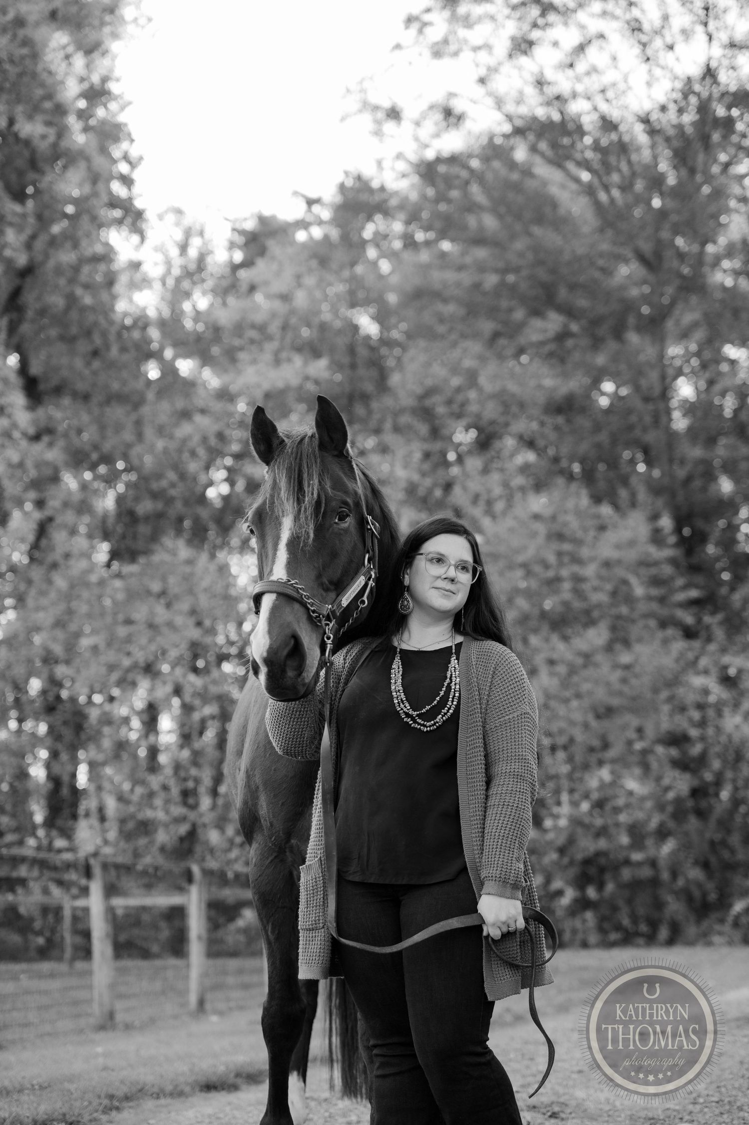 A black and white portrait of a horse and their companion standing together in a peaceful setting.