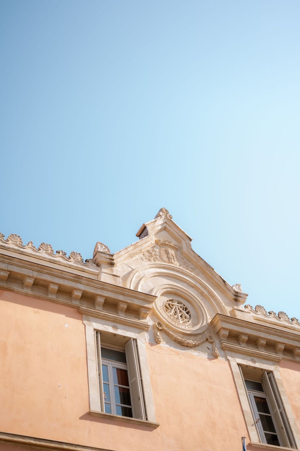 Ornate architectural details of a Mediterranean style building with beige walls and decorative window frames.