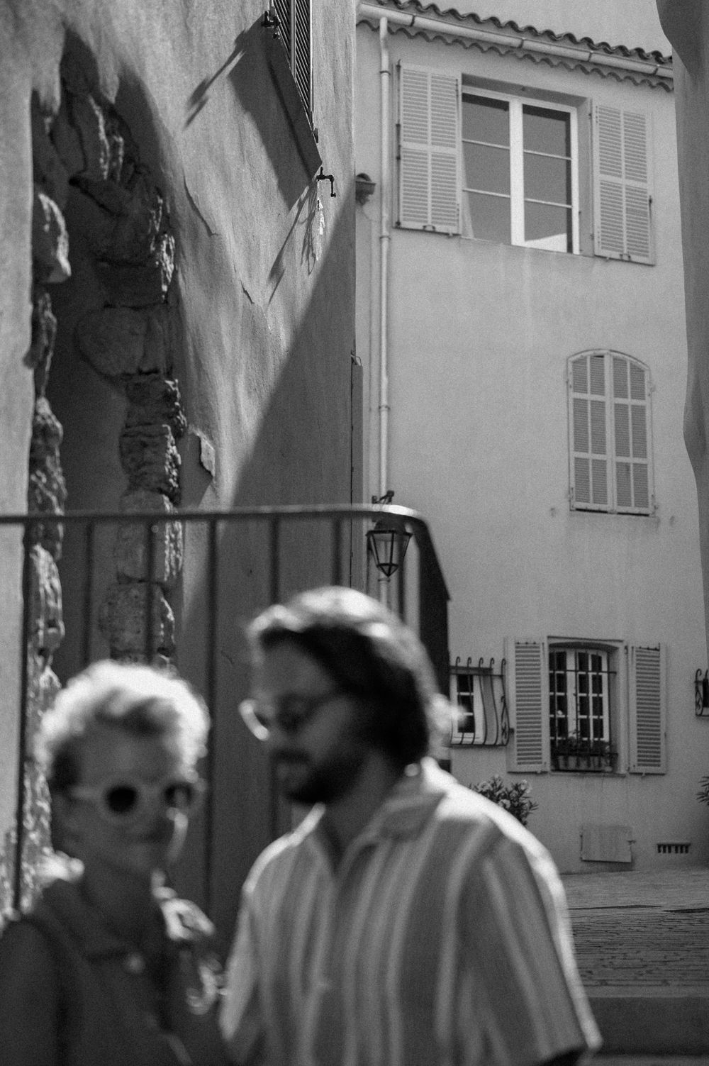 Group of people walking along a historic street with traditional architecture in black and white.
