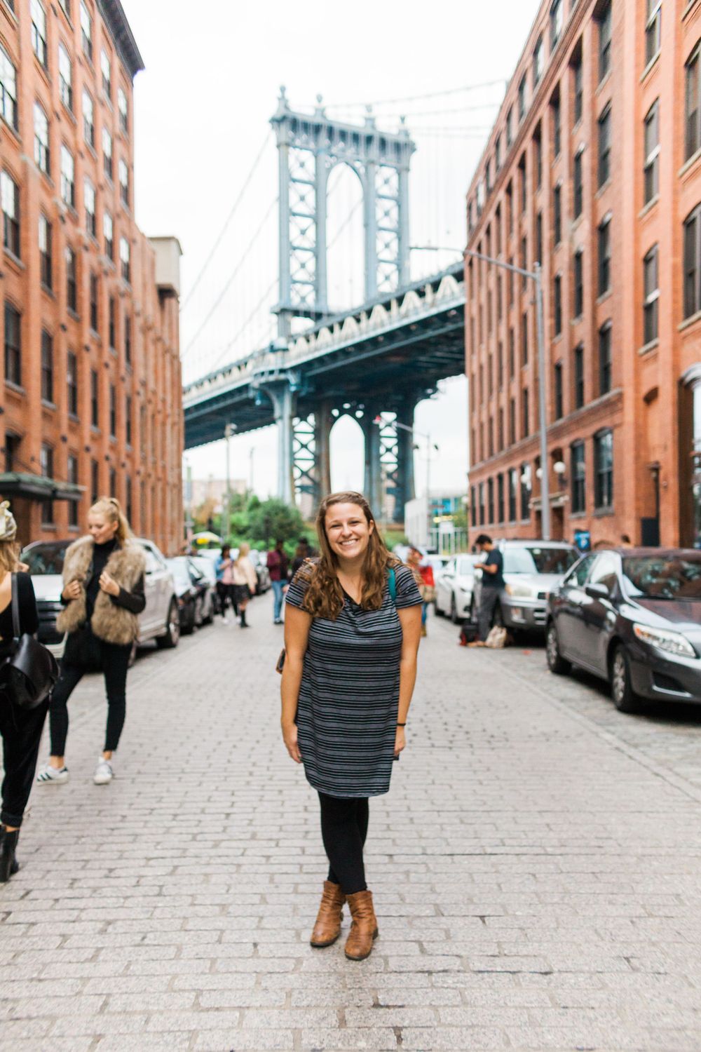 woman in DUMBO section of Brooklyn with the bridge behind her