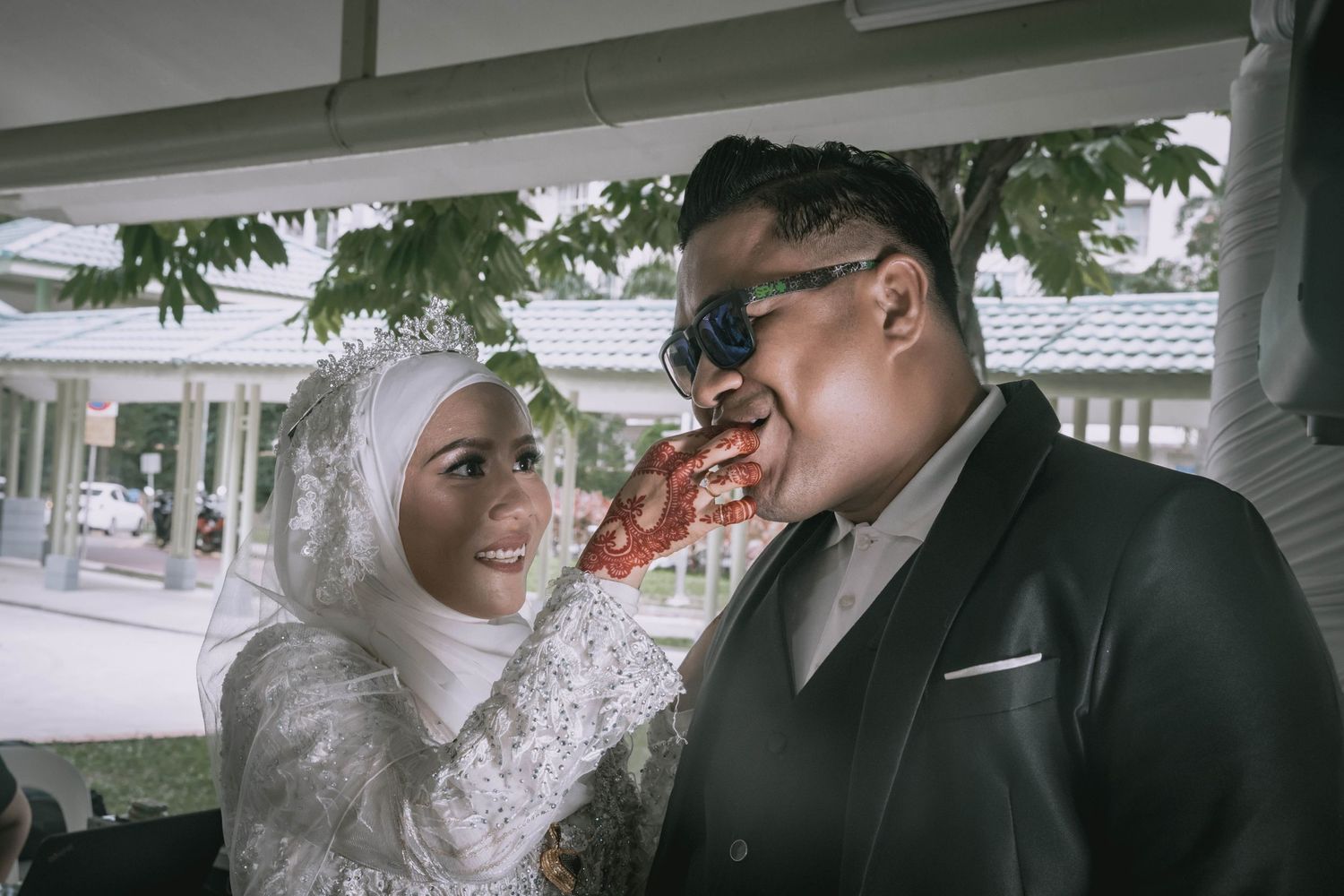 Candid outdoor wedding moment under covered patio with white decor.