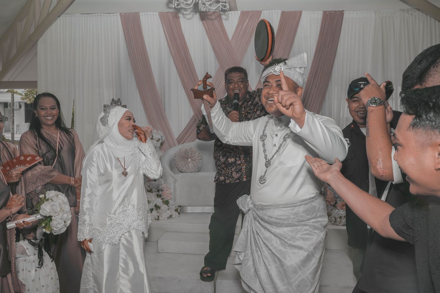 Wedding celebration with guests dancing and celebrating in decorated white tent venue.