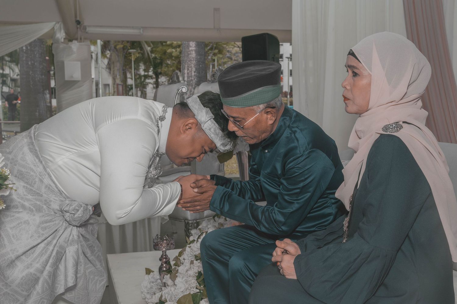 Traditional Muslim wedding moment showing respect between family members in formal attire.