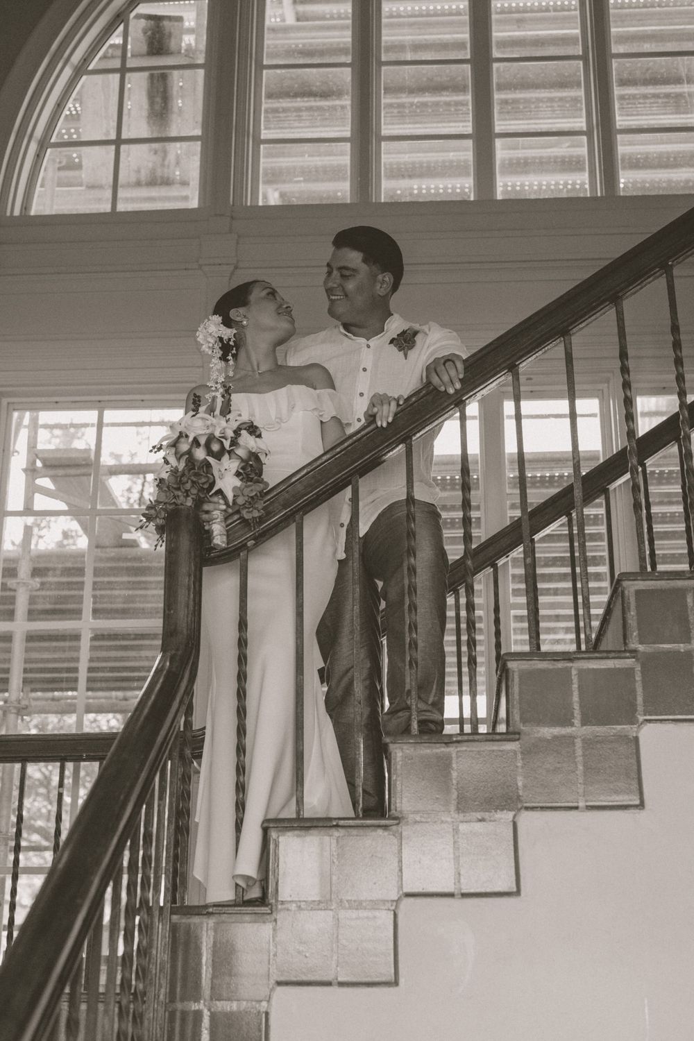Black and white portrait of wedding couple sharing intimate moment on staircase.