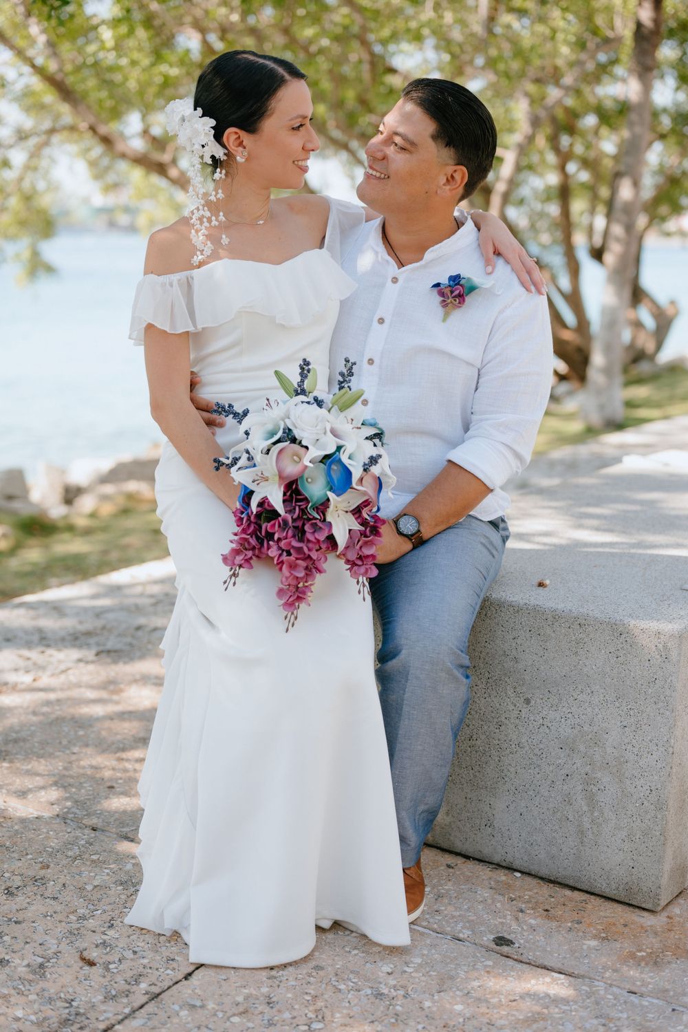 A coastal wedding portrait featuring a vibrant bouquet and seaside backdrop.