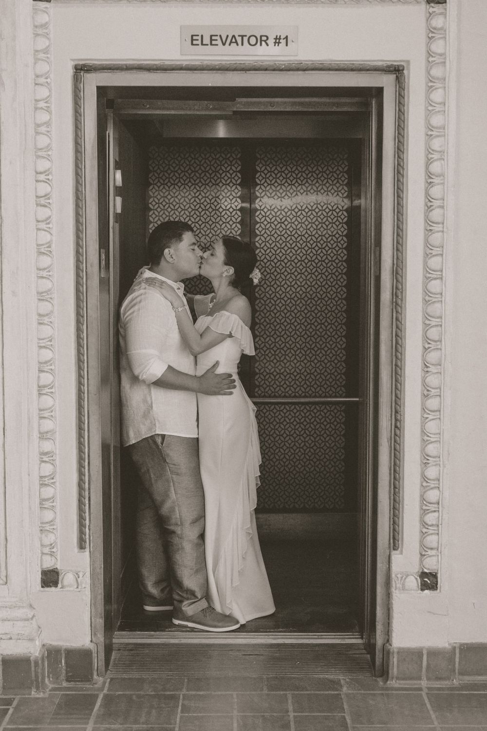 Romantic black and white photo of wedding couple embracing in vintage elevator.