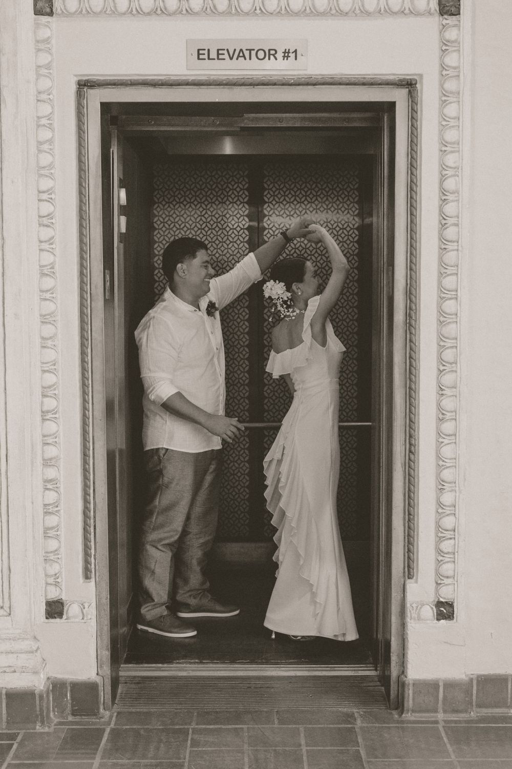 A couple dances together inside a vintage elevator during a wedding photo session.