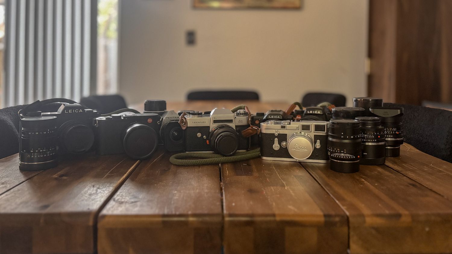 Professional camera gear collection arranged linearly on wooden table.