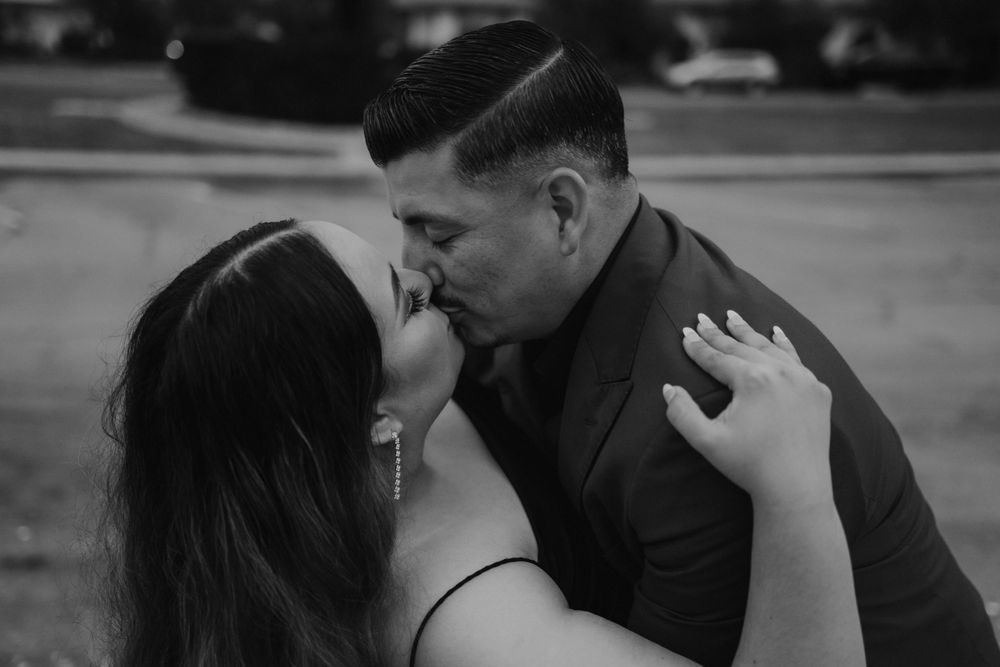 An intimate black and white portrait of a couple sharing a tender moment outdoors.