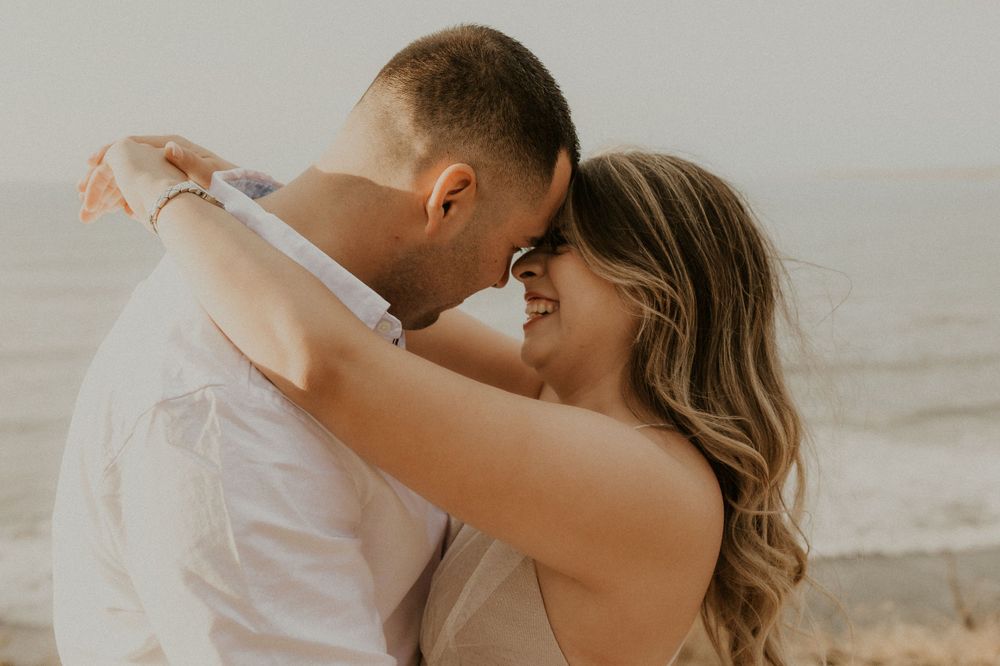A tender moment between a couple embracing on a sunny beach.