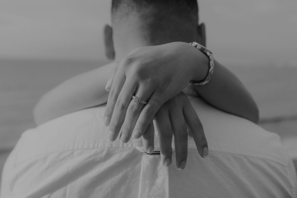 Close-up of hands with engagement ring embracing in black and white.