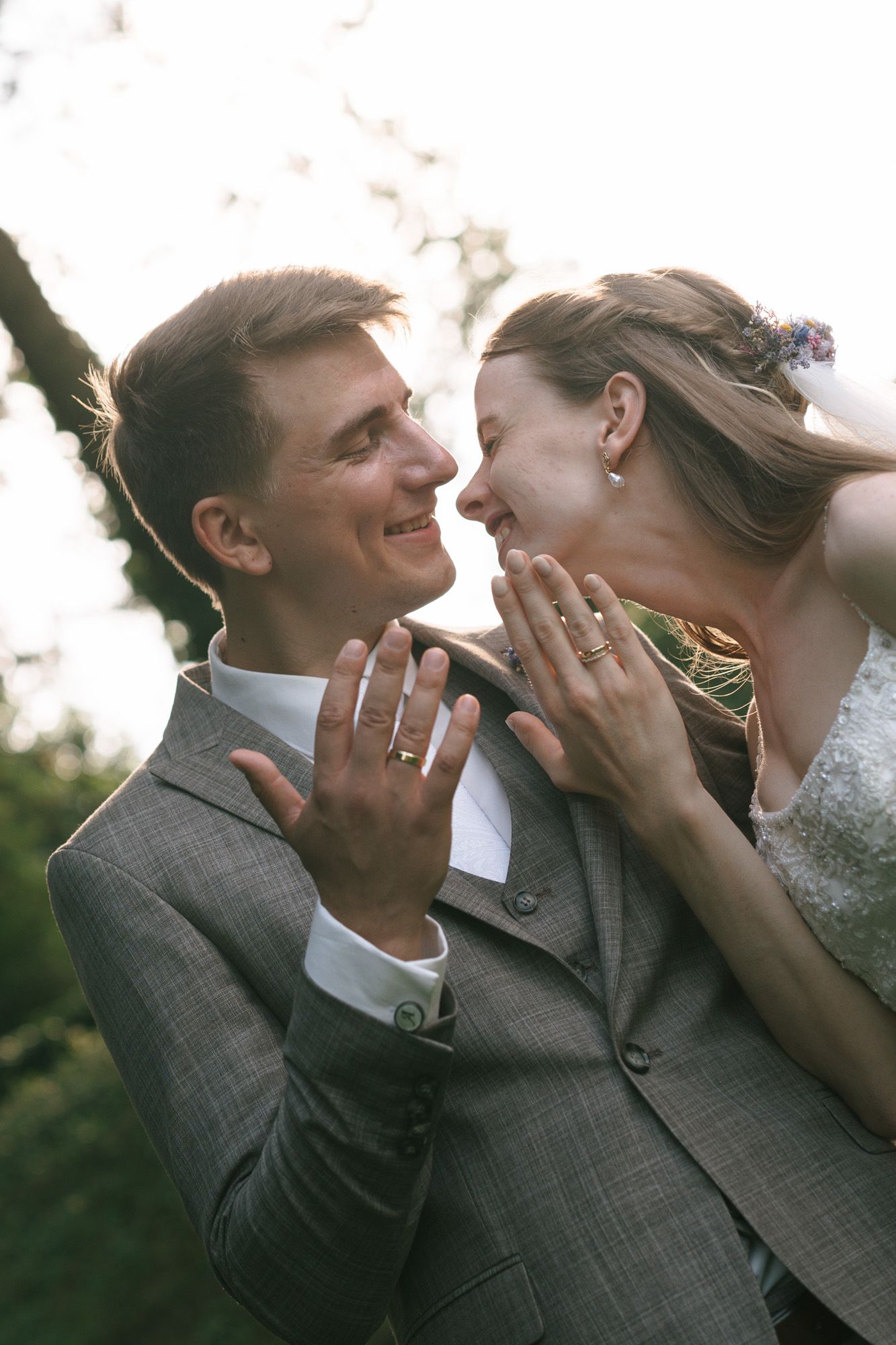 A joyful wedding couple shares an intimate moment while showing their rings.