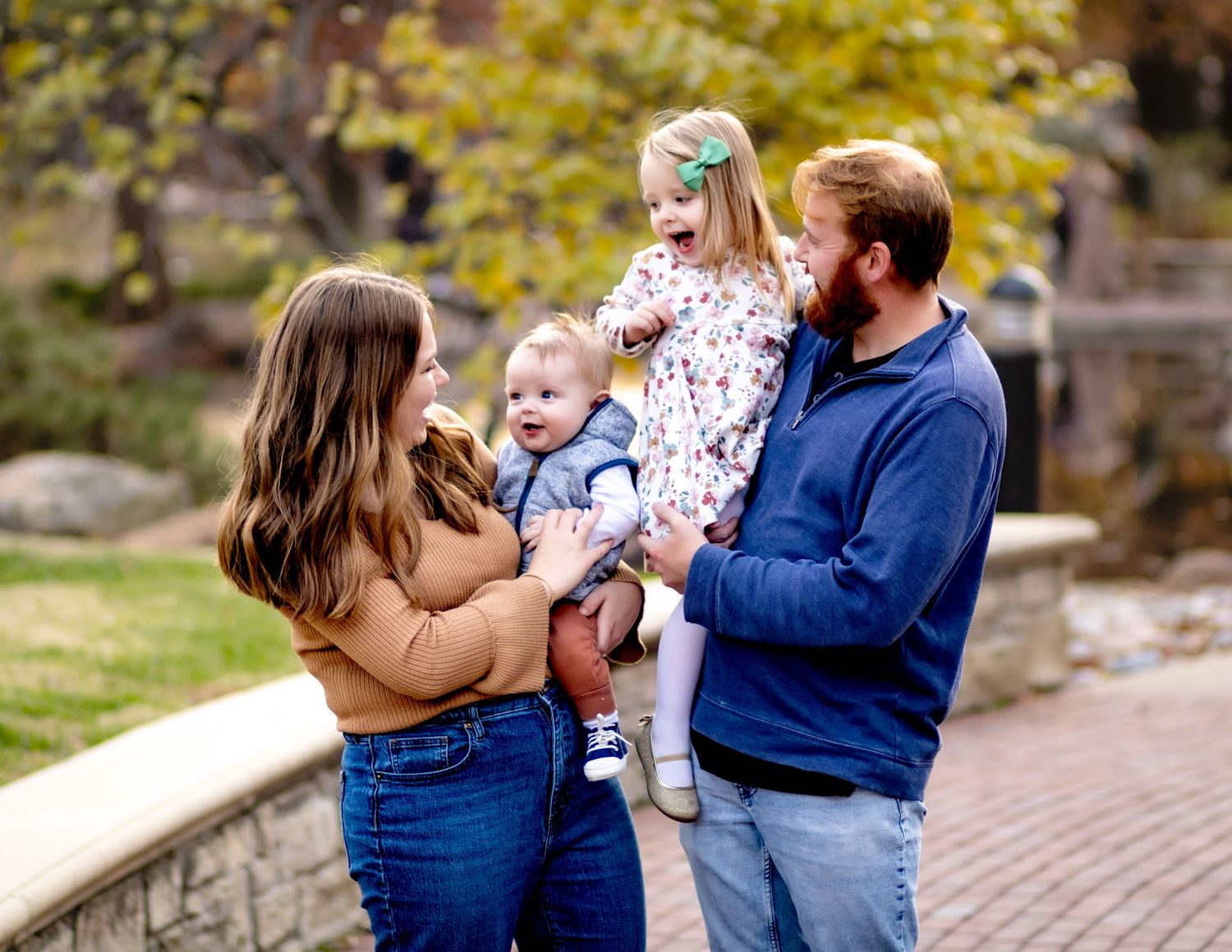 A family in coordinating blue outfits shares a joyful moment together in an autumn park setting.