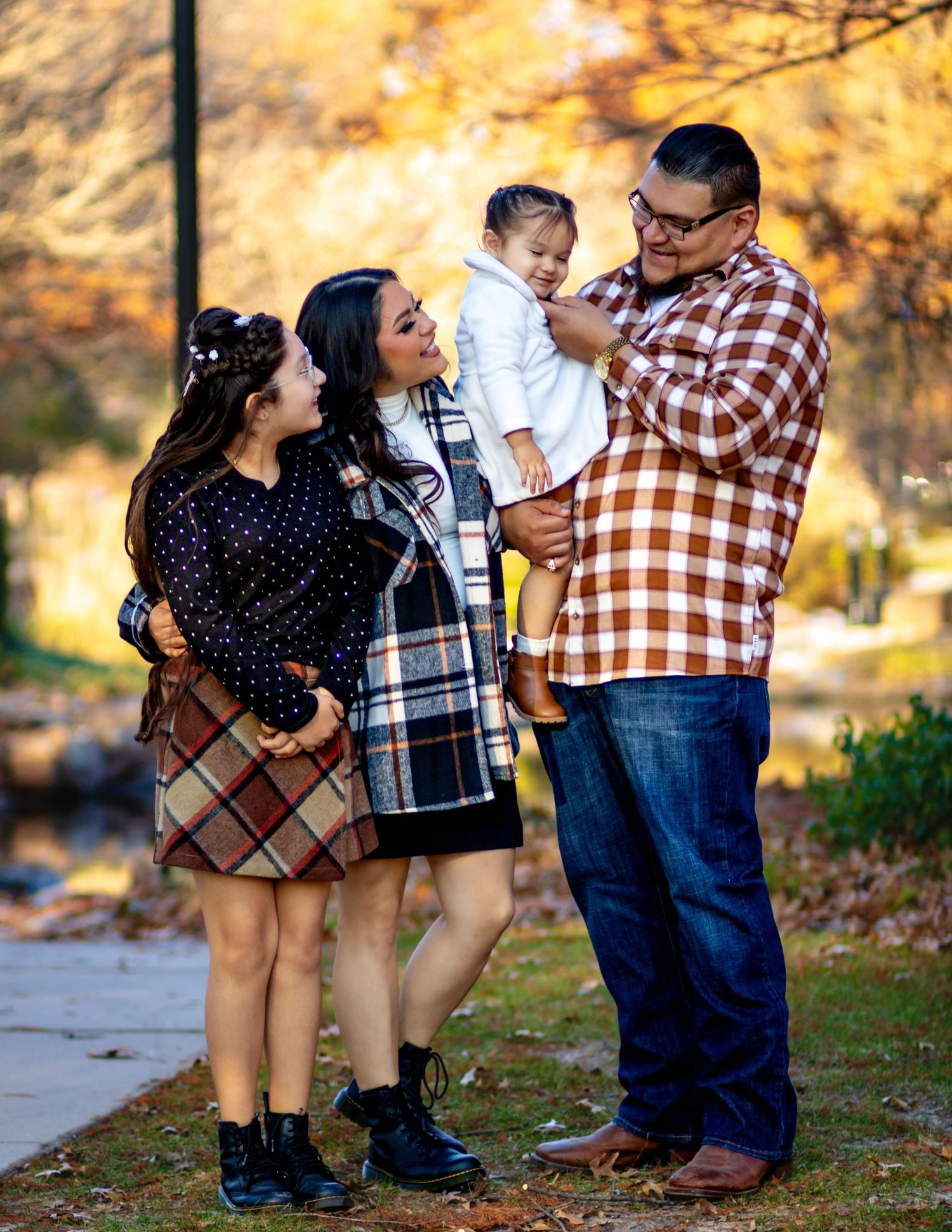A family shares a joyful moment together outdoors during autumn with golden foliage in the background.