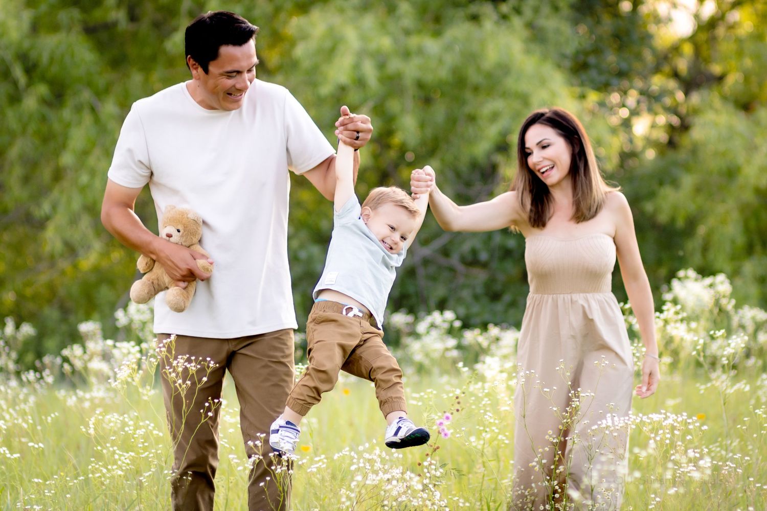 Happy family enjoying a playful moment together in a wildflower meadow during golden hour.