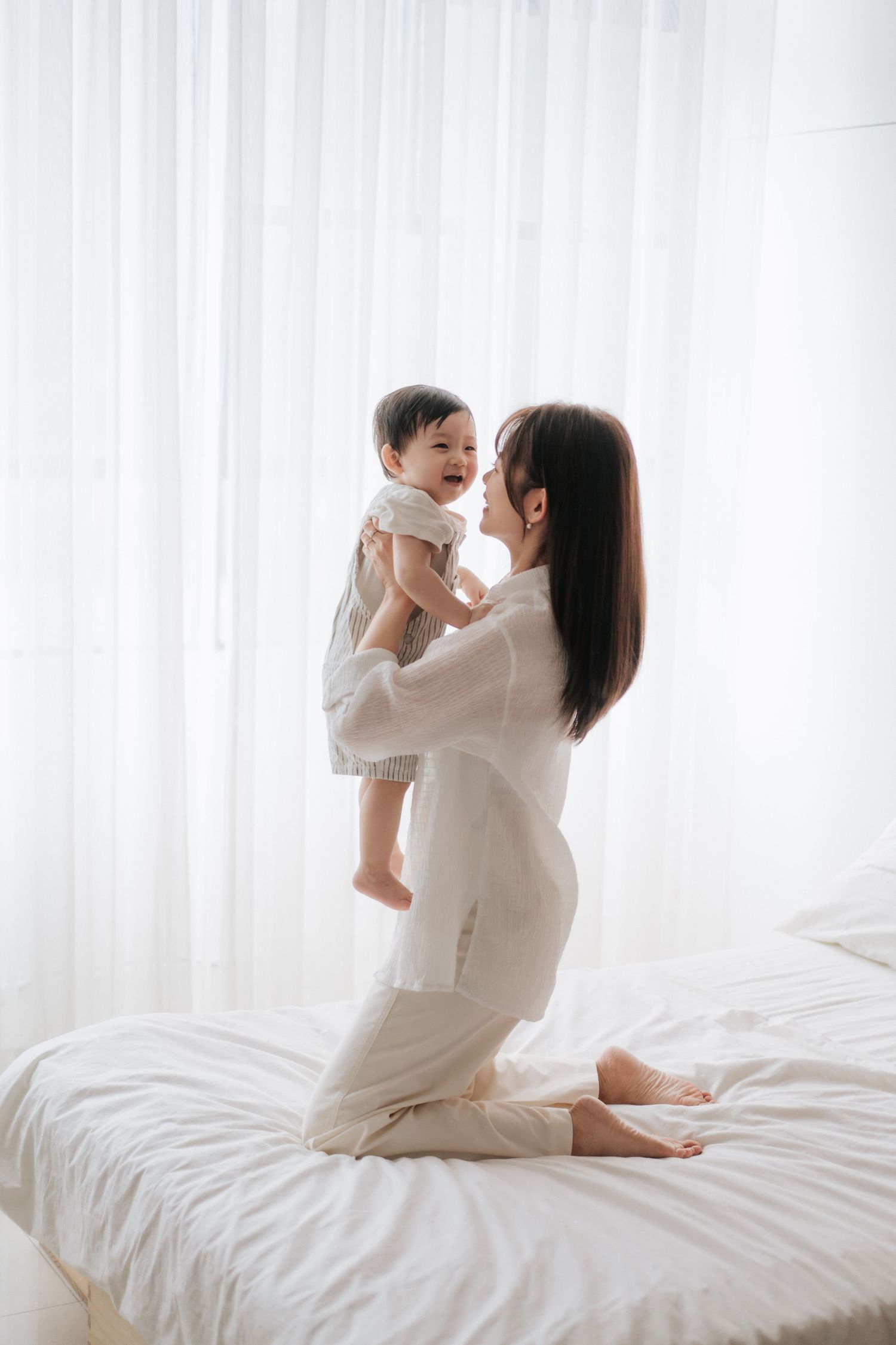 A parent and child share a joyful moment playing together in warm sunlight by a window.一位家長和孩子在溫暖的陽光下，於窗邊玩耍，享受著快樂的時光。