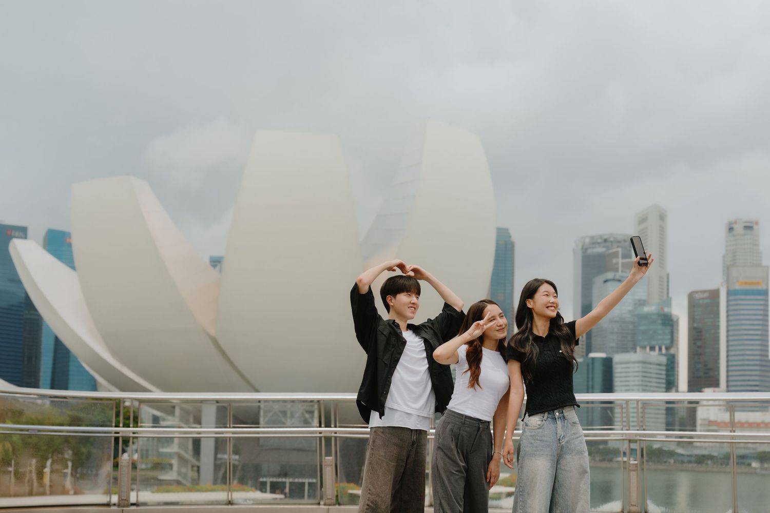 Three young friends take a selfie in front of the ArtScience Museum in Singapore's Marina Bay.