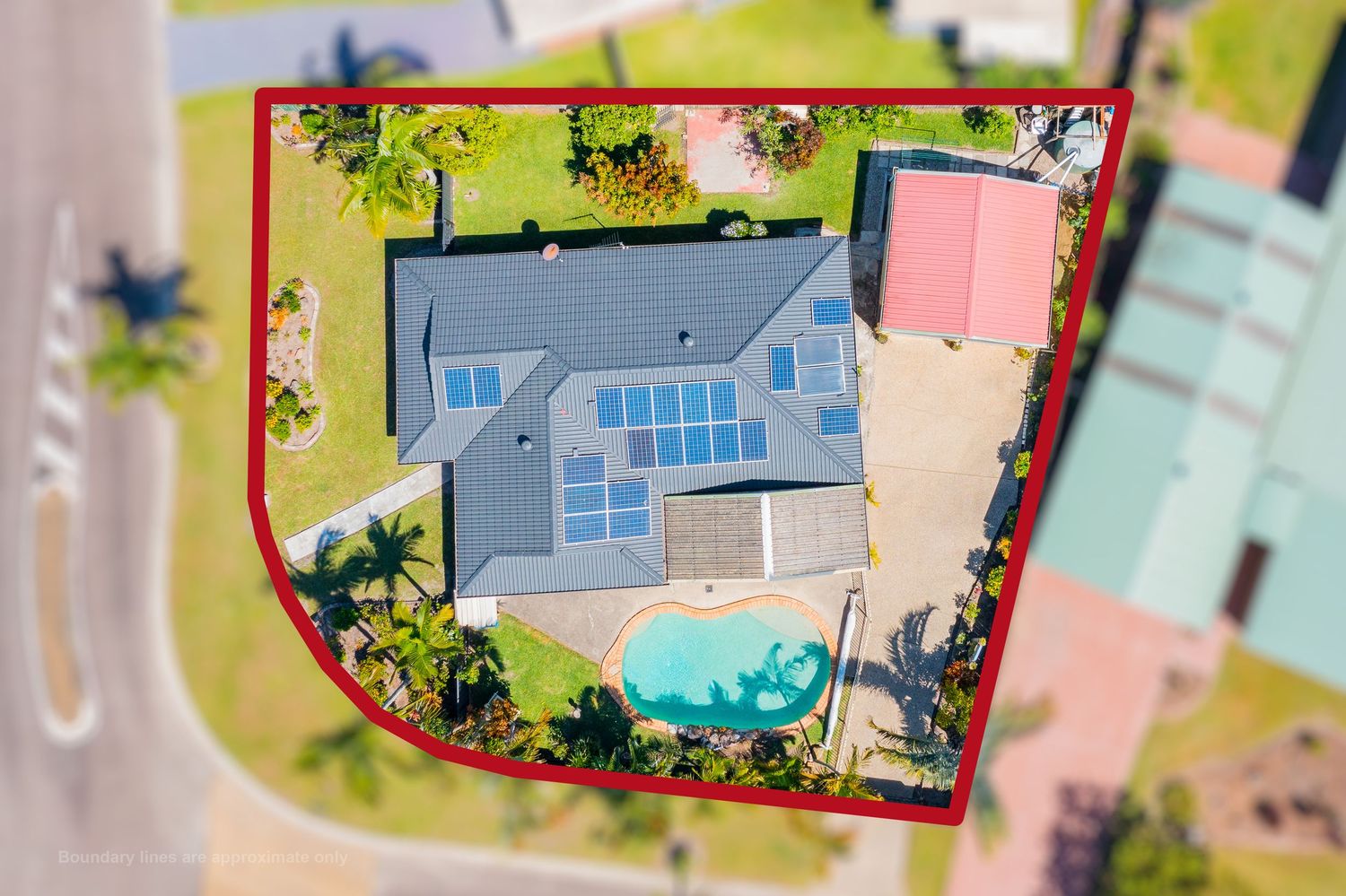 Aerial view of a house with a pool and solar panels, property boundary outlined in red, in a suburban area.