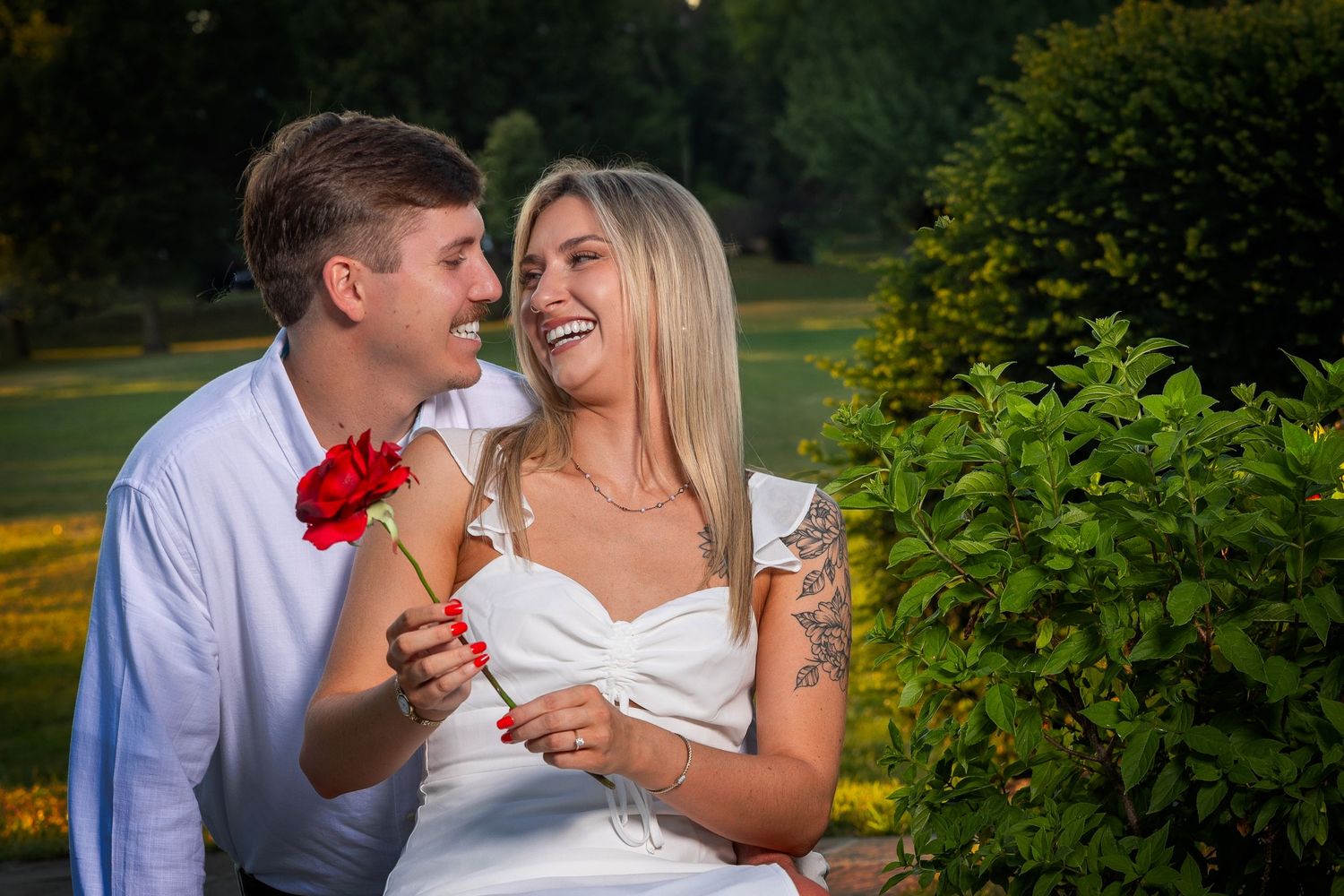 A romantic couple shares tender moments together in a lush garden setting during a golden hour photoshoot.