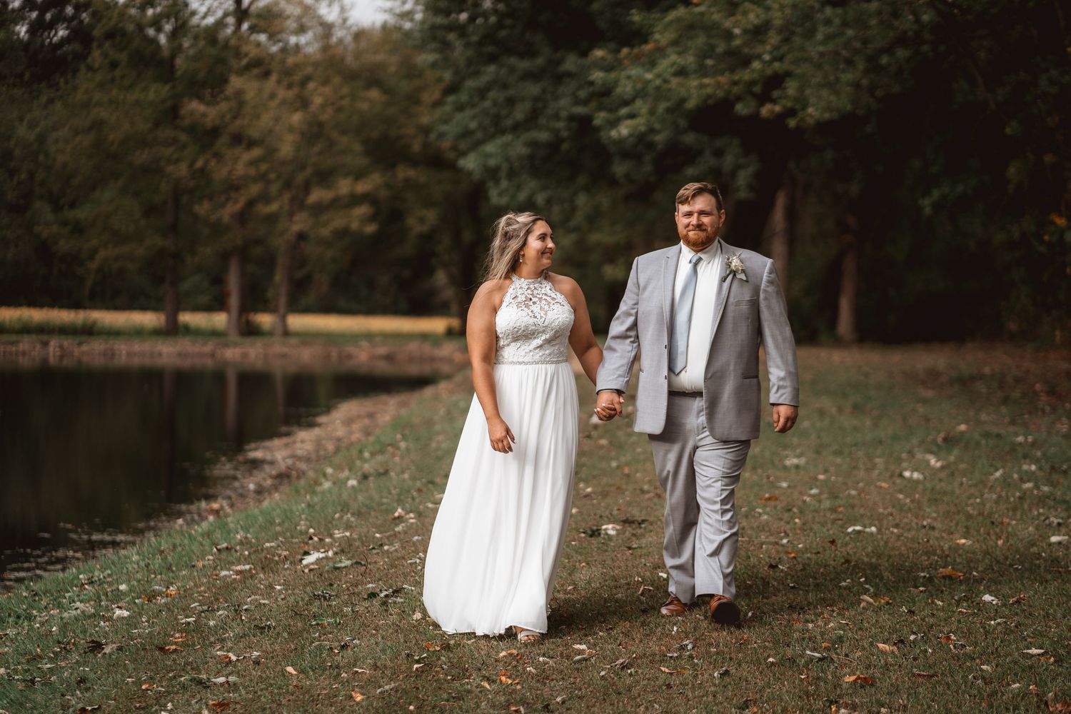 A romantic autumn wedding scene with natural landscaping and lakeside views.