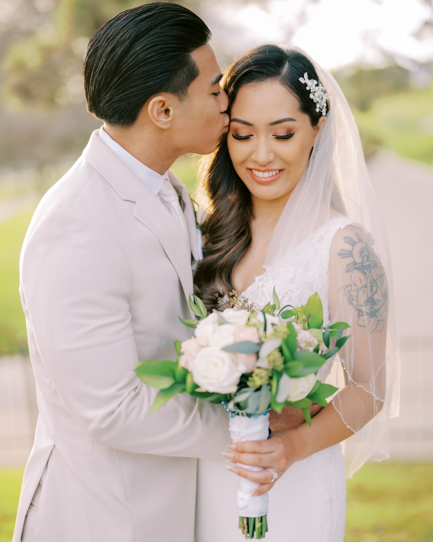 Romantic outdoor wedding portrait with white floral bouquet and delicate veil.