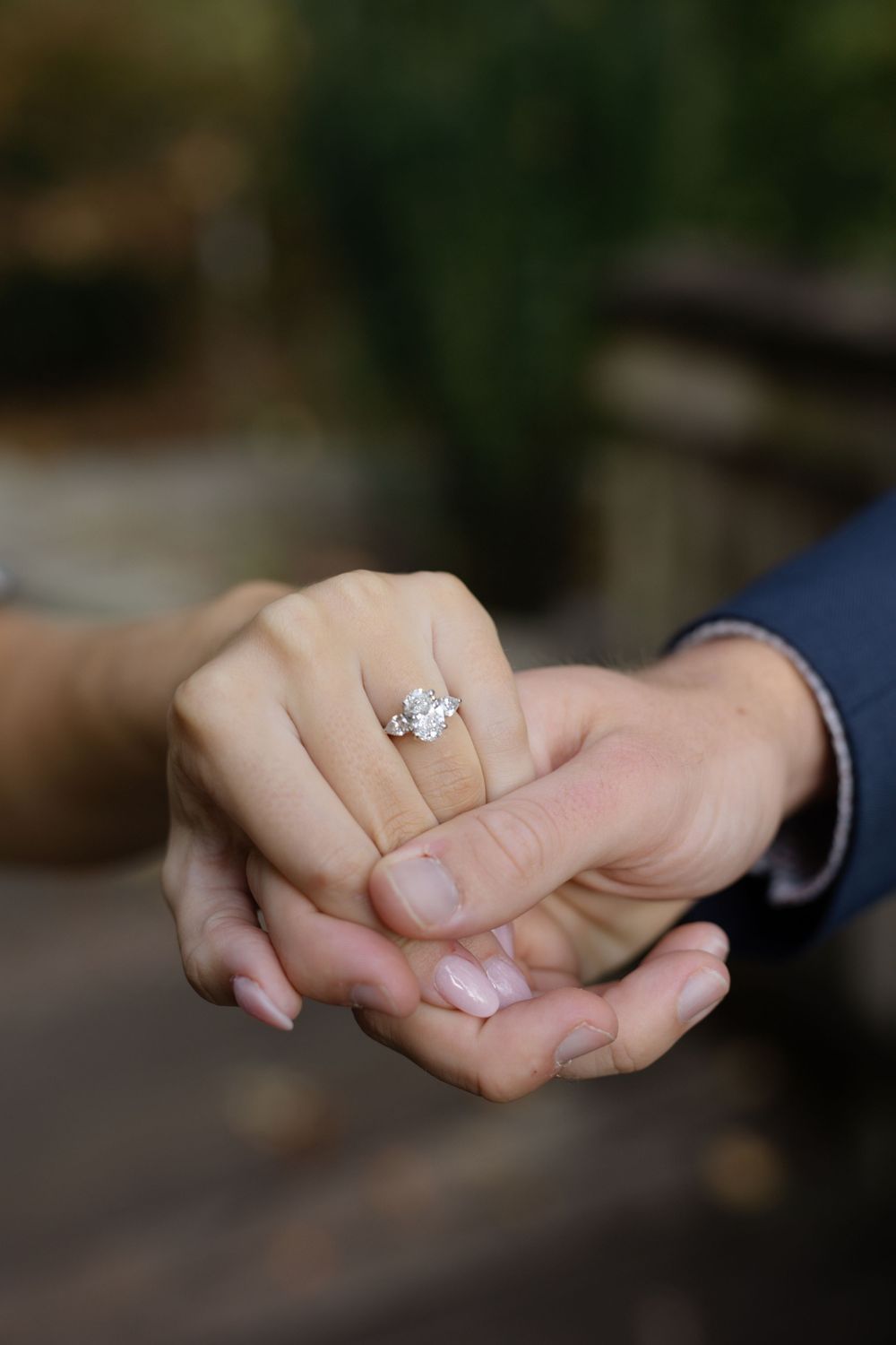 Multiple angles of a diamond engagement ring being displayed on a hand.