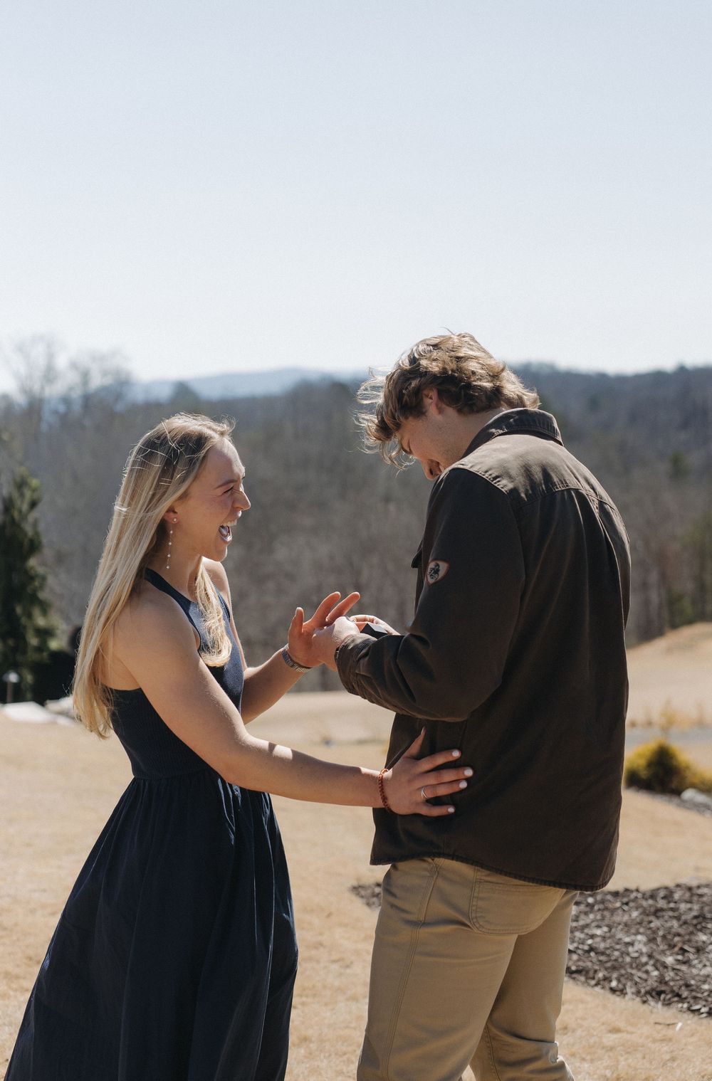 Candid engagement photos showing joyful reactions during a surprise proposal outdoors.