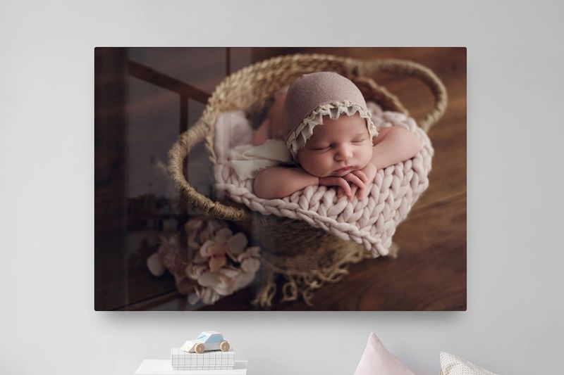 Newborn baby wrapped in delicate lace blanket sleeps peacefully on rustic wooden surface in warm lighting.