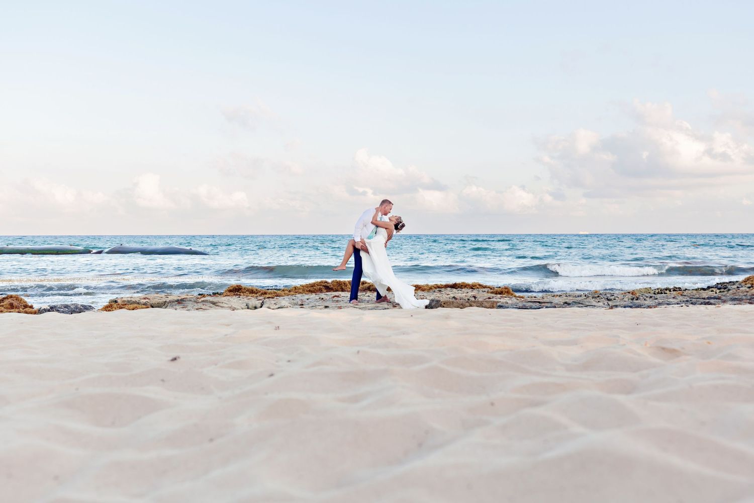 Romantic beachside wedding portrait with waves crashing in background.