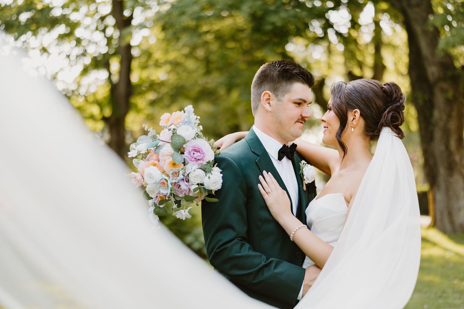 A romantic wedding portrait silhouetted against a bright sky.