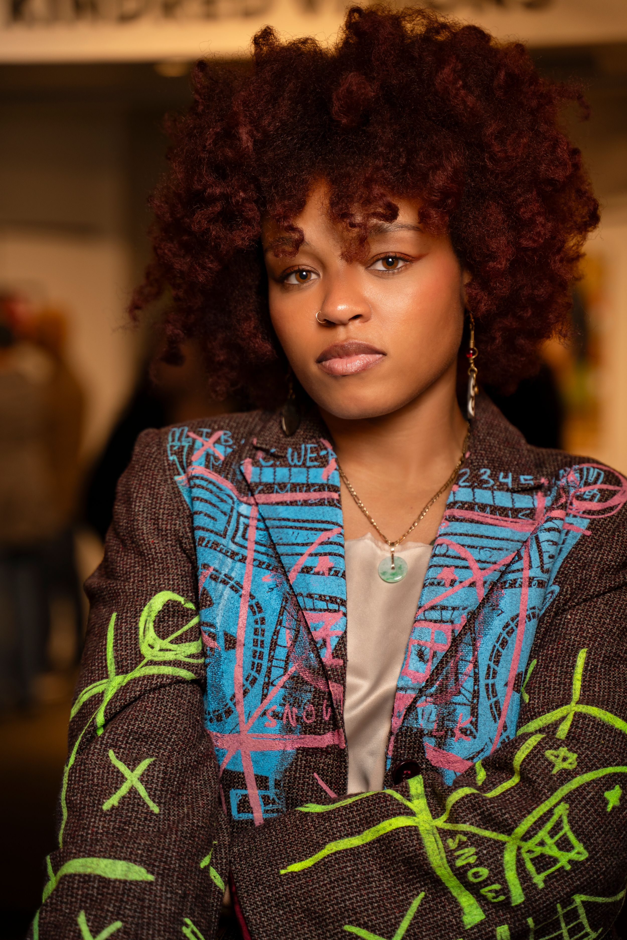 A fashion portrait showcasing a textured sweater with blue and green geometric patterns against a warm-toned background.