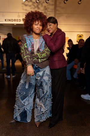 A stylish outfit featuring a patterned sweater and distressed denim in an artistic indoor setting.