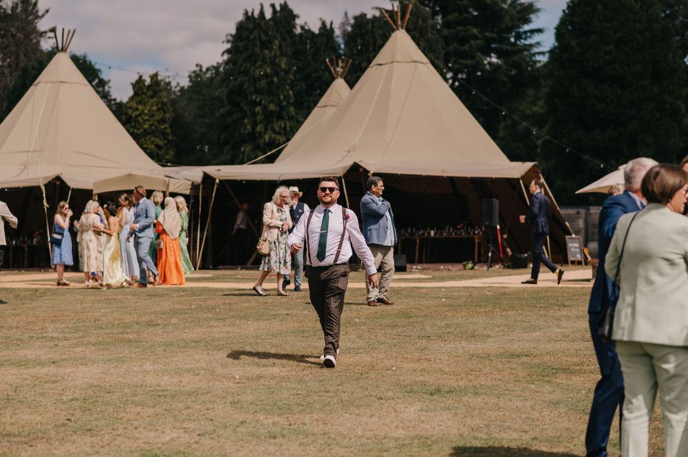 Beige canvas teepee tents set up in a grassy field during an outdoor gathering.