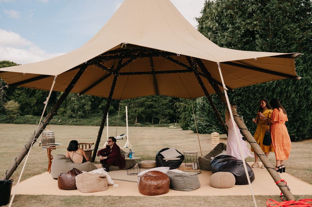 A series of outdoor lounge areas with beige shade sails and brown ceramic planters arranged on a patio space.