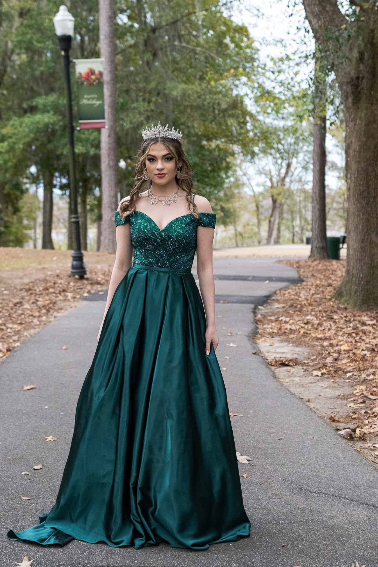 High school senior wearing emerald green prom dress and tiara posing for Charleston SC prom portraits in park