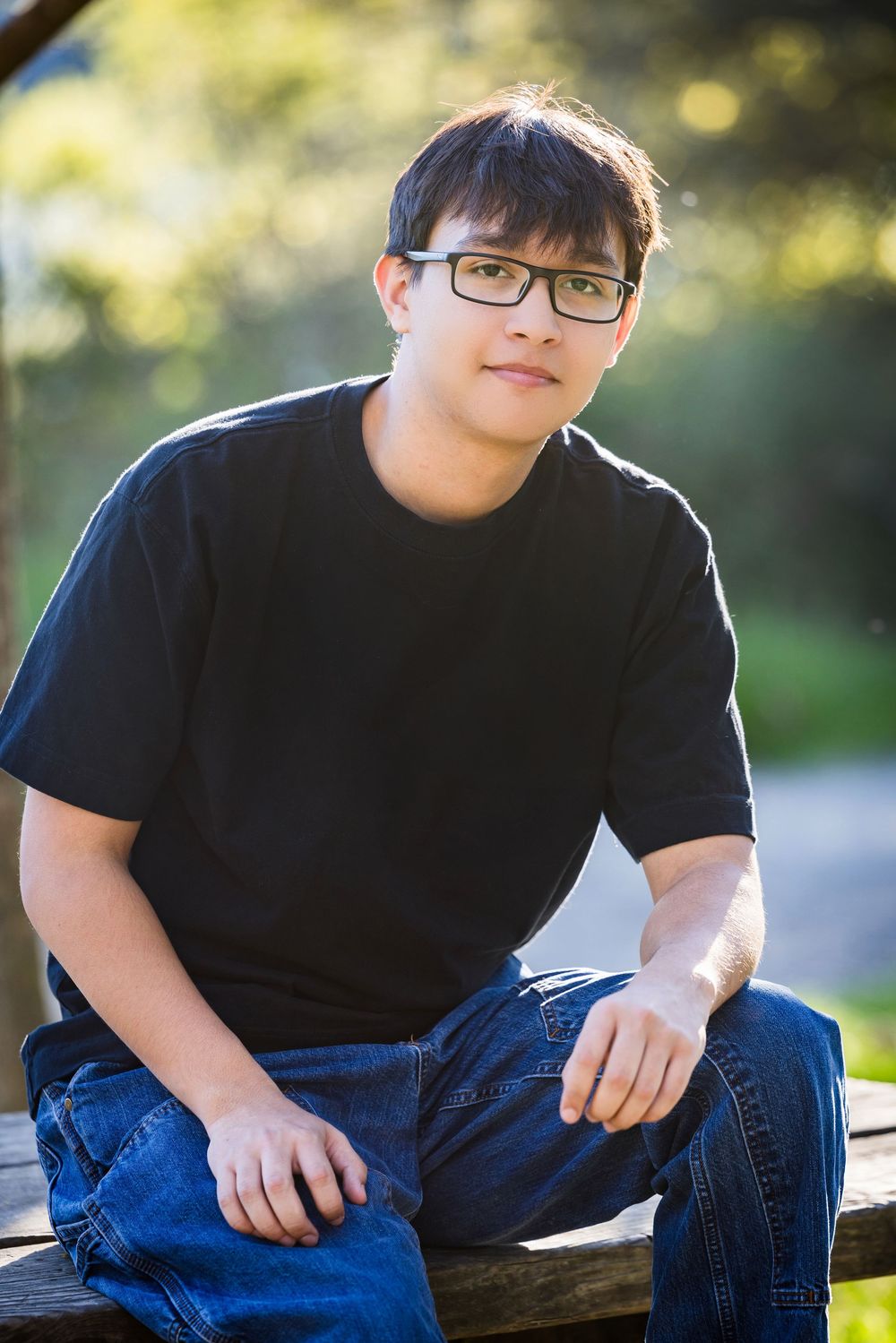 Multiple shots of someone wearing a black t-shirt and jeans sitting on a wooden log in bright outdoor lighting.