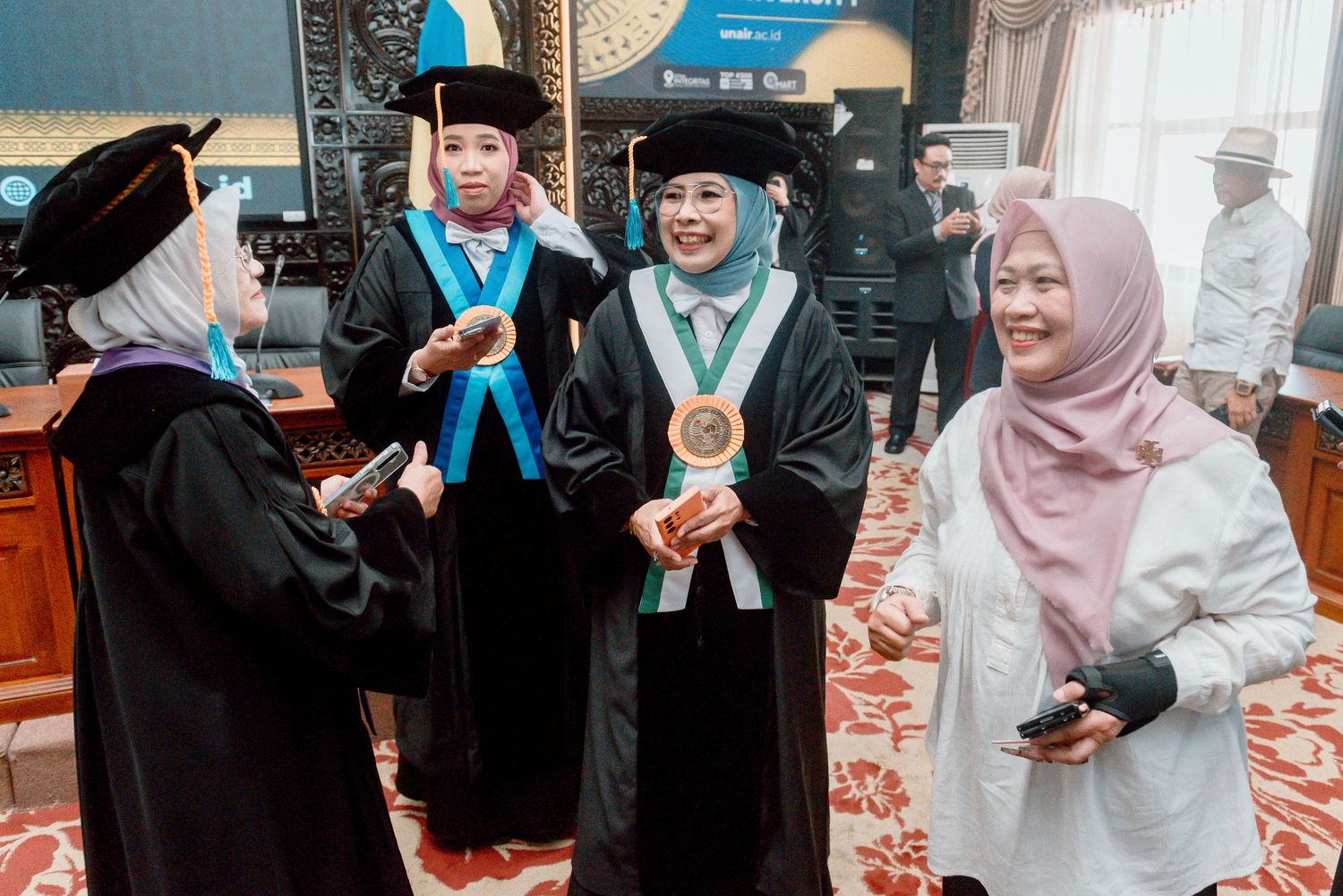 Students in graduation caps and gowns gather for photos during a graduation celebration.