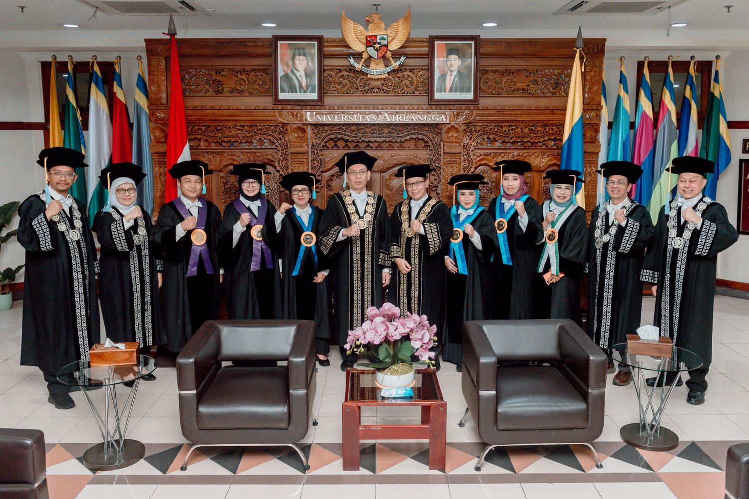 Graduates in traditional black academic regalia stand in rows during a formal commencement ceremony.