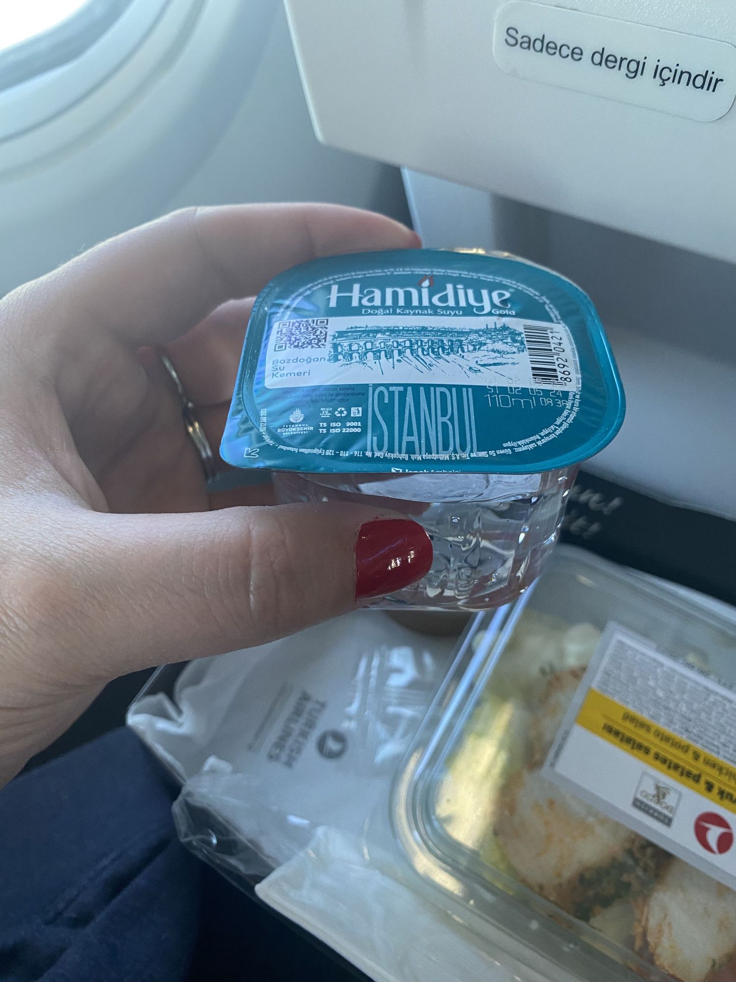 A sequence of photos showing Turkish Airlines branded packaged meals and snacks being opened on an airplane tray table.