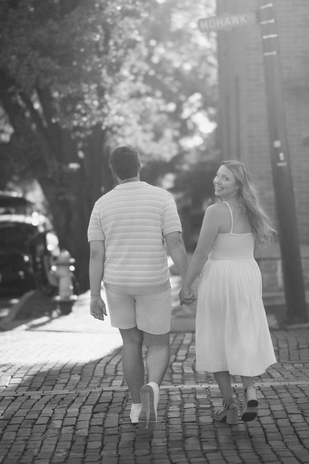 A couple holding hands while walking down a cobblestone street in black and white photography. German Village Engagement session