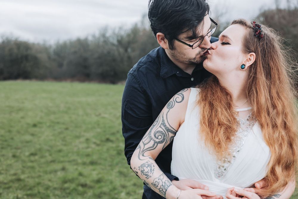 A romantic couple in winter attire shares intimate moments during an outdoor photo session in a natural setting.