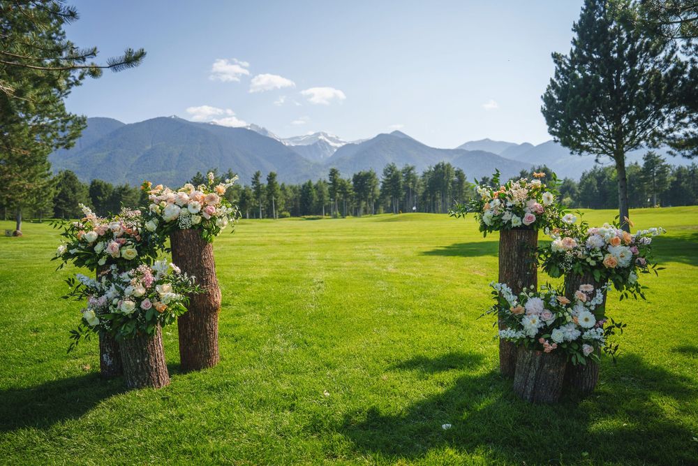 Mountain landscape with floral arrangements on rustic wooden stands in a green meadow during summer.
