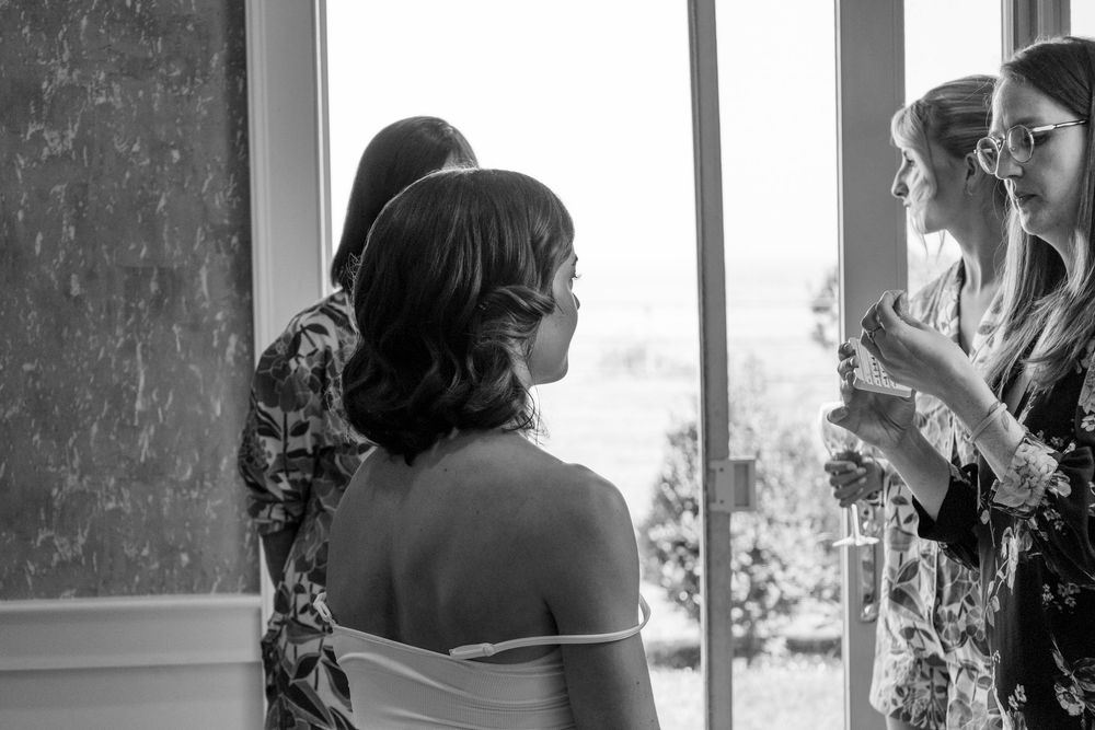 A black and white photo series shows a couple in intimate moments by a window during a wedding celebration.