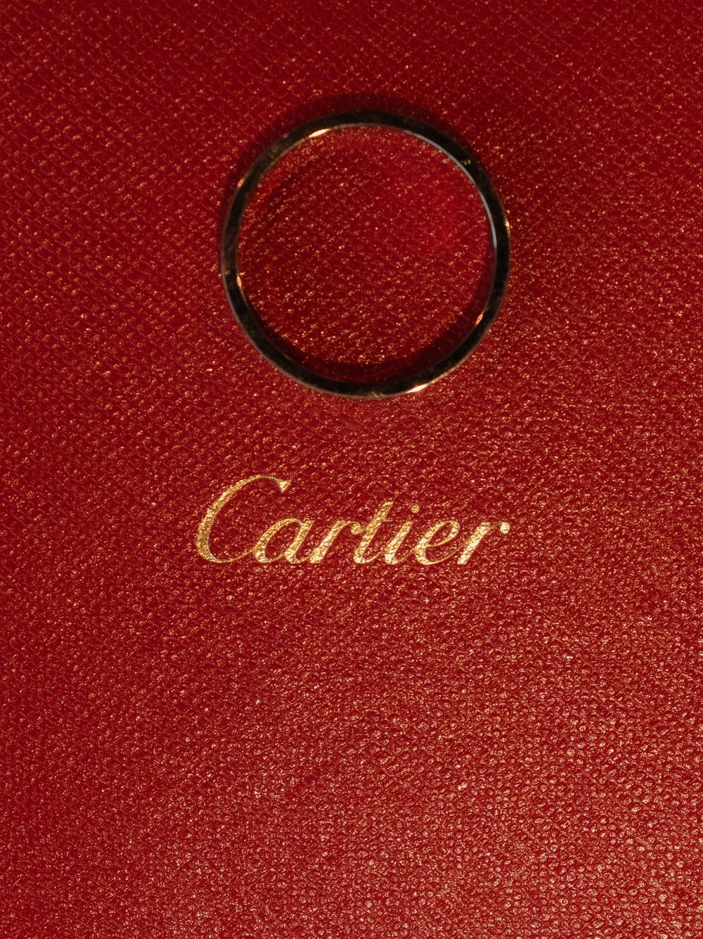 Cartier wedding rings displayed on a luxurious red textured background.
