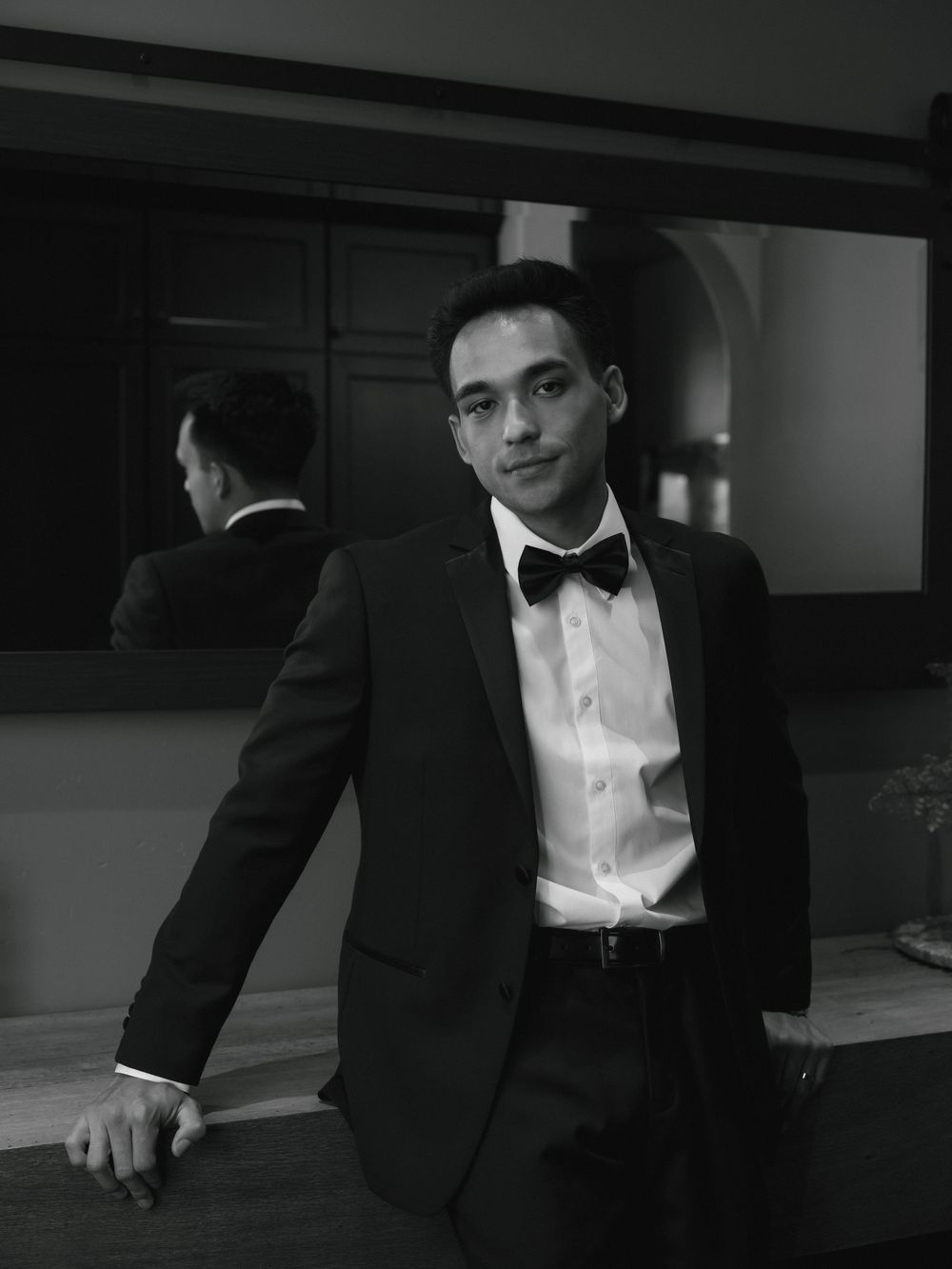 A formal black and white portrait of someone in a tuxedo and bowtie.