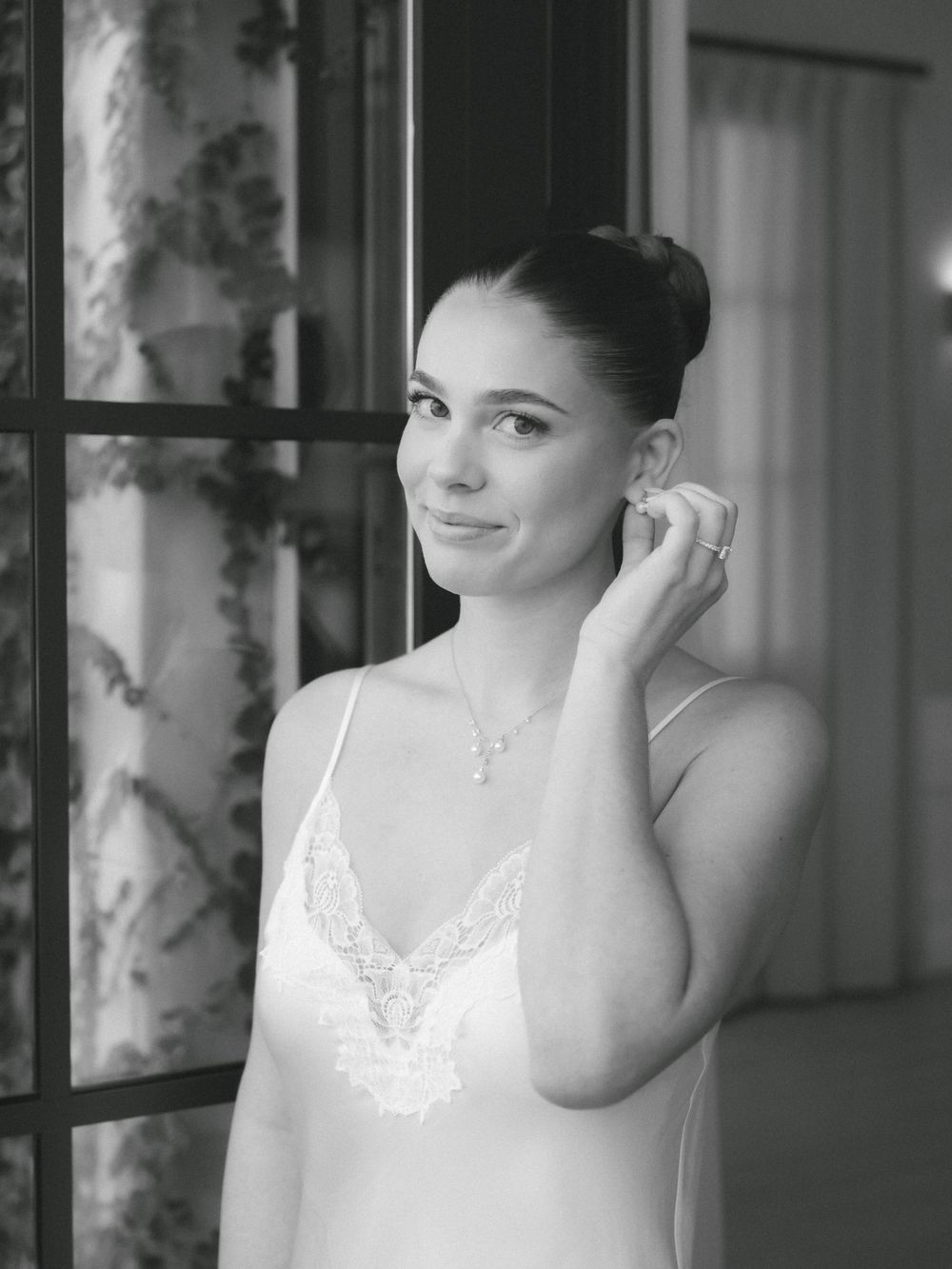 Black and white portrait of someone in a white lace dress preparing for a special occasion.