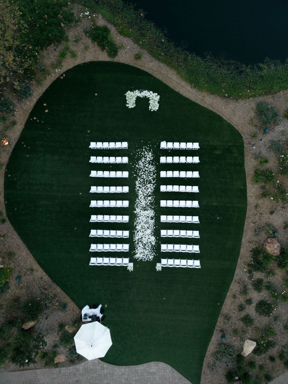 Aerial view of white chairs arranged on a green lawn for an outdoor wedding ceremony.