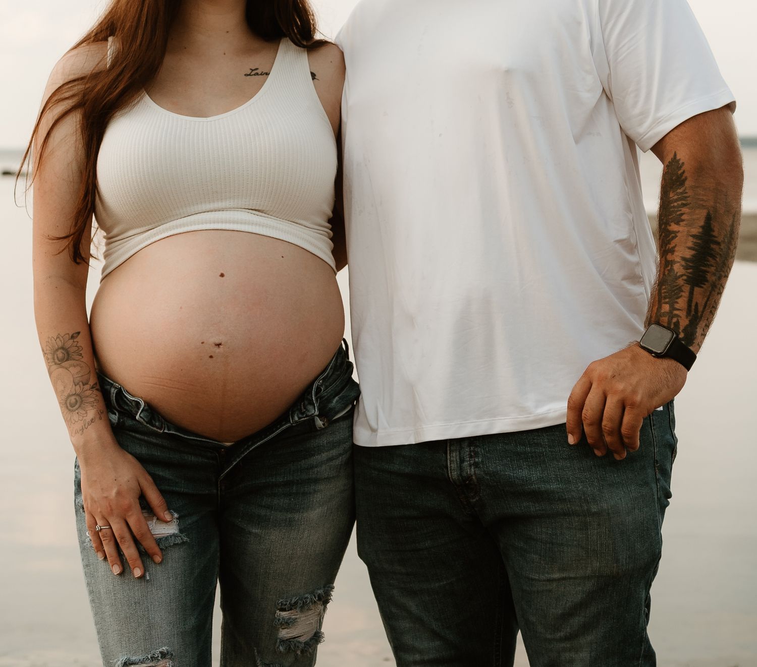 A series of pregnancy progression photos showing a growing baby bump in jeans and white tops against a neutral background.