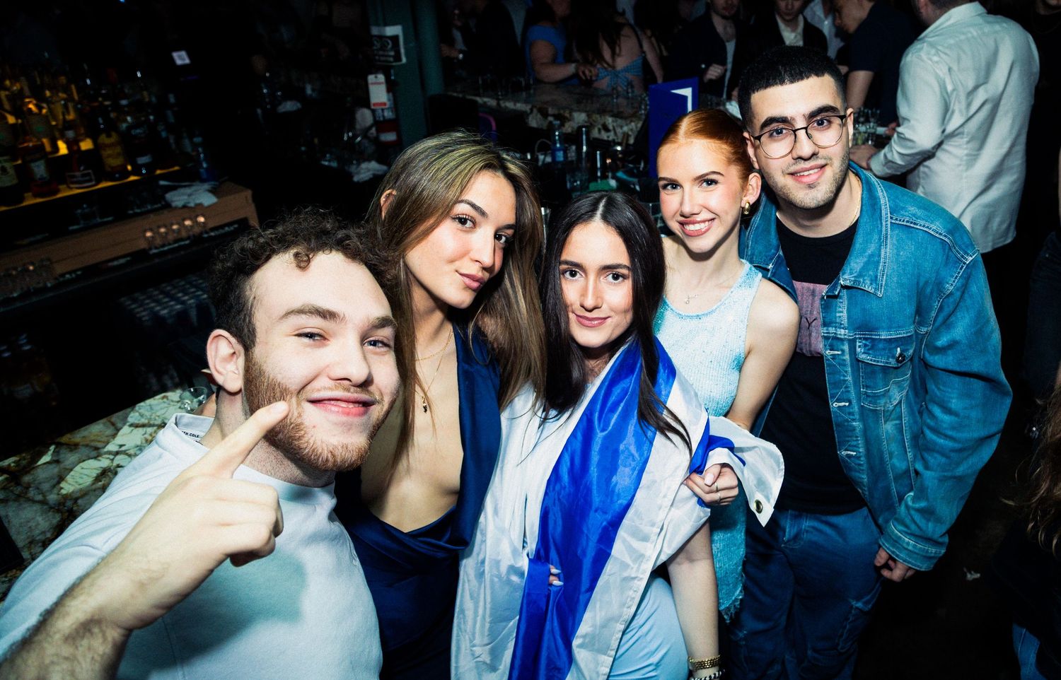Friends enjoying a night out at a party with colorful lighting and energetic atmosphere.