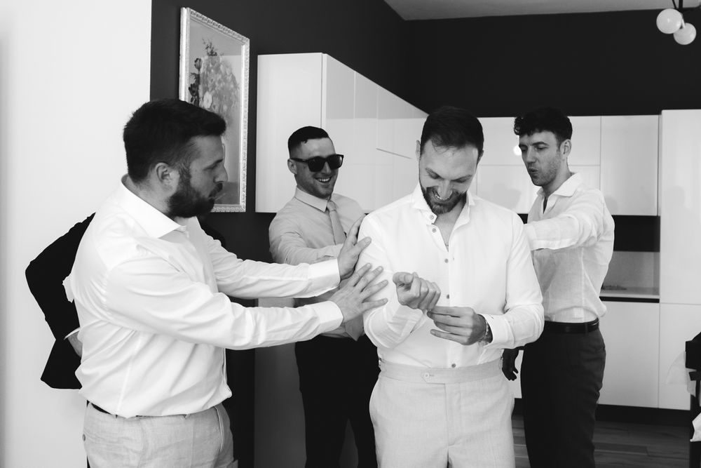 Testimoni aiutano lo sposo a vestirsi prima della cerimonia a Villa Casa Rossa Imperia